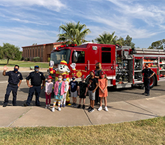 Kids posing with firefighters, firetruck, and Dalmatian mascot 